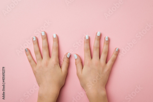 Two women's hands with makeup on a pink background.