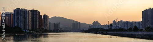 Panorama shot of Shing Mun River, Sha Tin, Hong Kong during sunset, with dense buildings and promenade