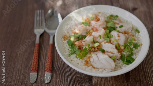 Boiled rice soup with fish and shrimp in bowl on wood background