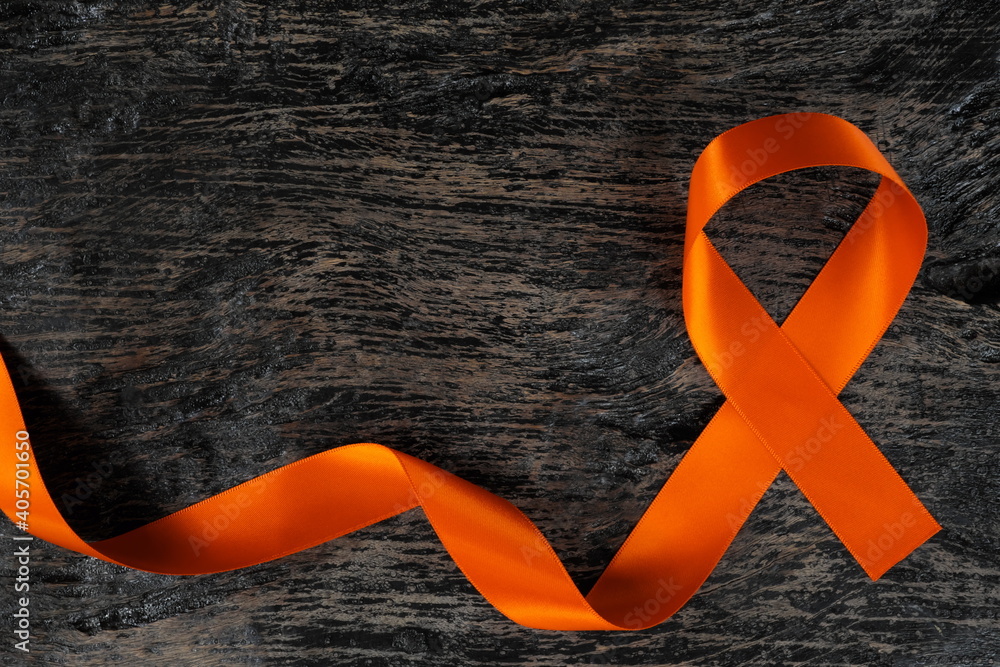Top view of orange ribbon on dark wood background. Leukemia, kidney cancer,  adhd, copd, malnutrition and hunger, multiple sclerosis and cultural  diversity awareness concept. Stock Photo