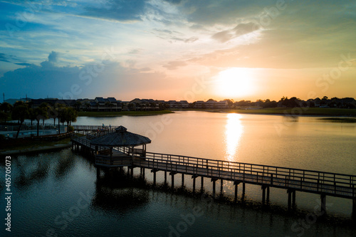 An aerial drone image of a wooden walking path over a lake during a sunset © Miralem