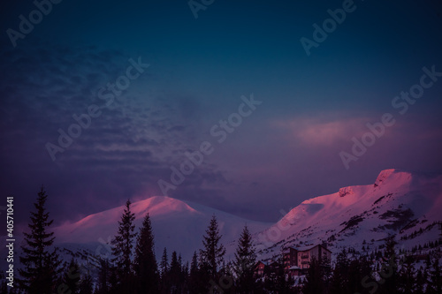 the first rays of the sun at dawn touch the snow-capped peaks of the mountains