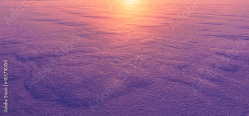beautiful blue and purple colored snow field surface illuminated by evening sunset , violet snow texture , original winter background