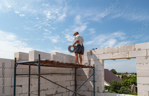 A worker builds the walls of a house from aerated concrete bricks.