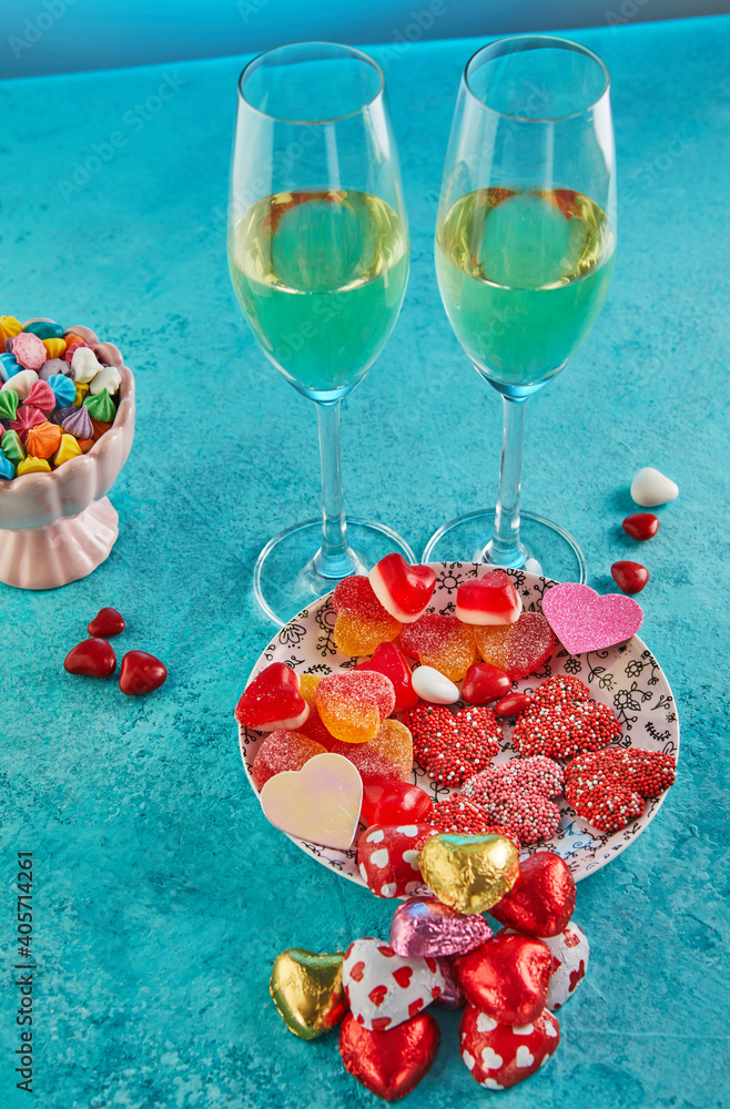 Valentine's day or romantic dinner with candy hearts, glasses of champagne and elegant table setting on a blue background