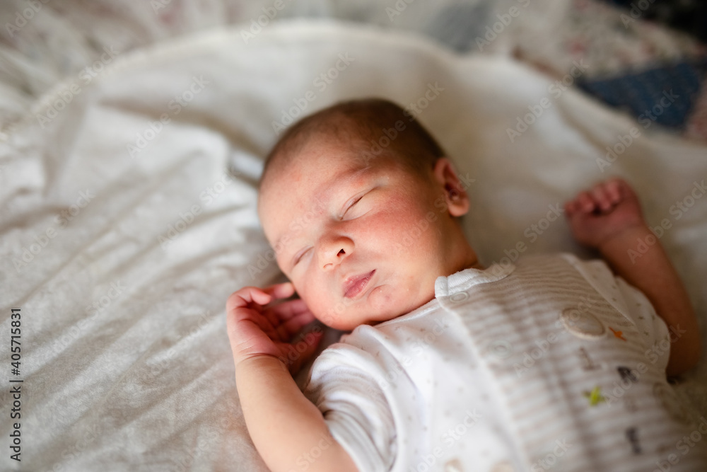 Newborn baby for the first time at home, lying in a blanket on the bed, smiling, yawning, pulling pens, falling asleep, baby's morning, baby products concept. Newborn baby for the first time at home, lying in a blanket on the bed, smiling, yawning, pulling pens, falling asleep, baby's morning, baby products concept.