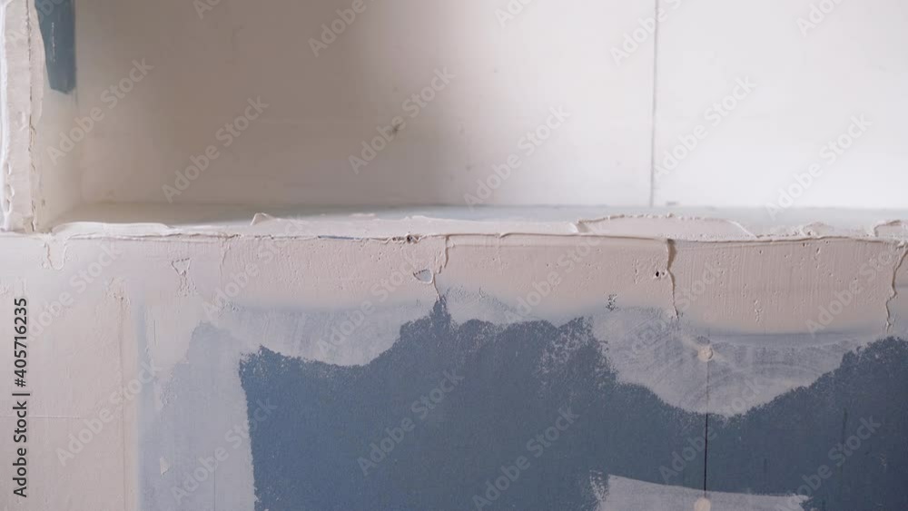 A person levels the wall while working using a drywall sanding trowel