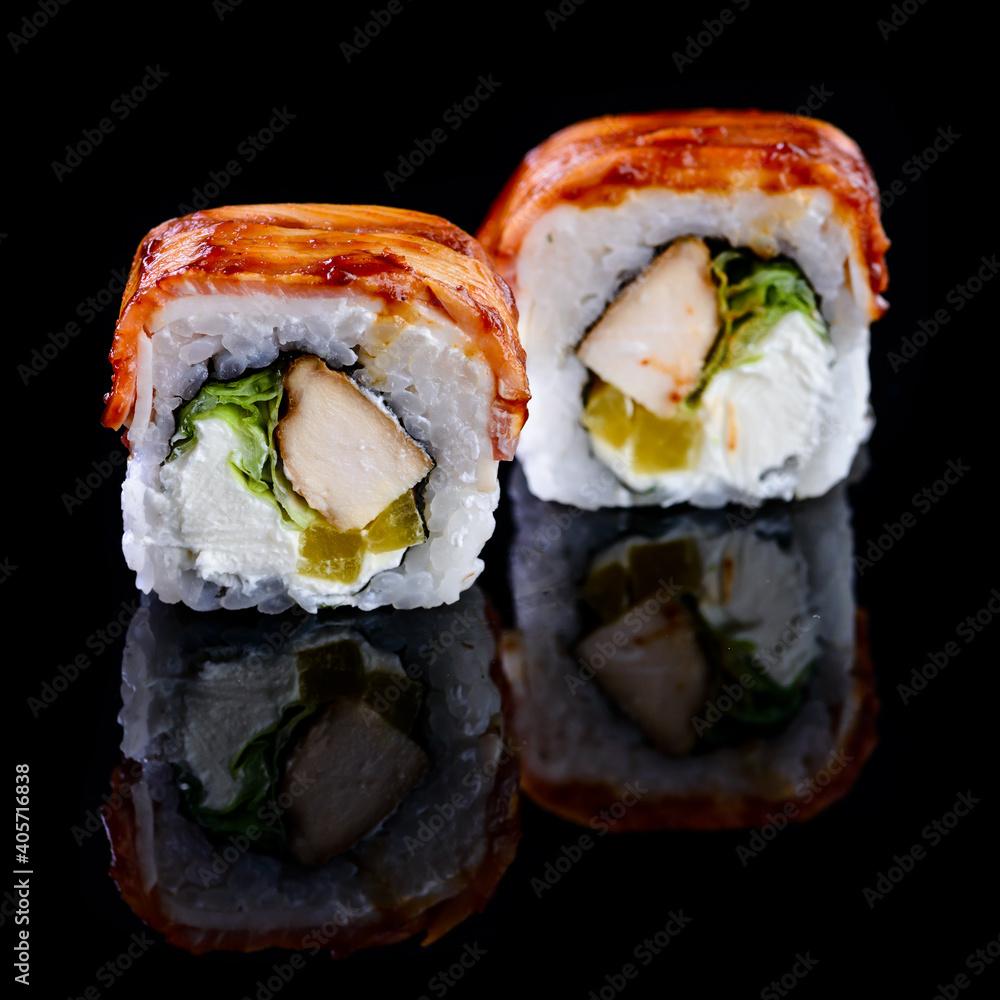 Concept of Asian cuisine. Two rolls of sushi with different fillings on a black background for Japanese menu. two sushi rolls couple isolated with reflection
