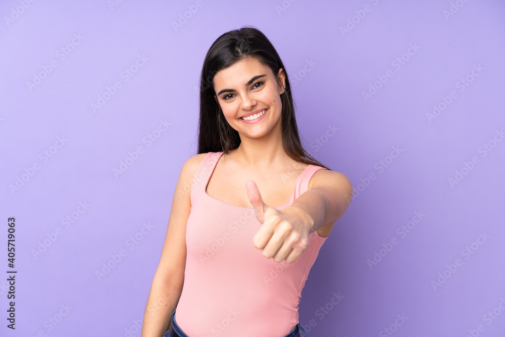 Young woman over isolated purple background with thumbs up because something good has happened Young woman over isolated purple background with thumbs up because something good has happened