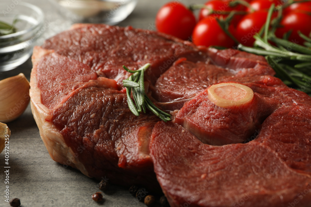 Fresh raw steak meat, herbs and spices on gray background