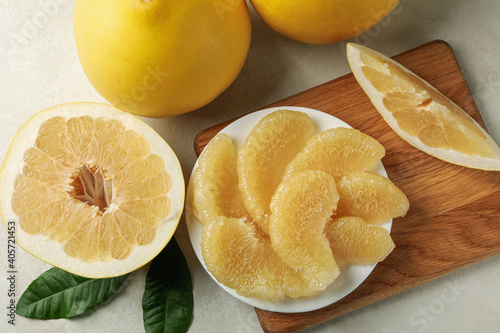 Ripe pomelo and plate with pomelo slices on white textured background photo