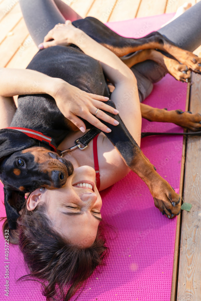 Fototapeta premium morning yoga concept with your pet. woman doing gymnastics with a beautiful doberman puppy in the morning park