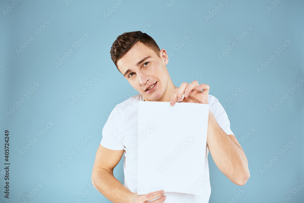 a man in a white t-shirt holds a sheet of paper copy space a man in a white t-shirt holds a sheet of paper copy space