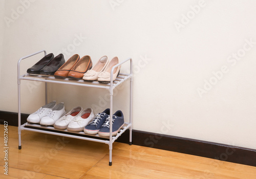 Small metal shoe shelf with women shoes on wooden floor
