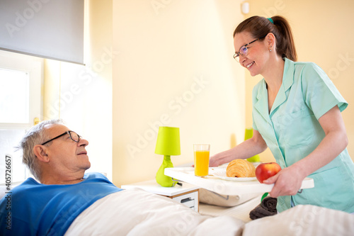Nursing home staff bringing breakfast for the senior man occupant of elder peoples home