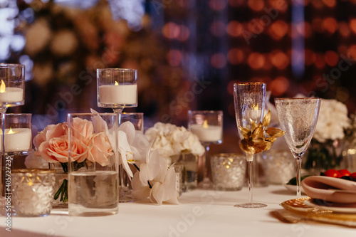 Decorated table setting background. Glasses, candles in the candlesticks, and roses. Banquet