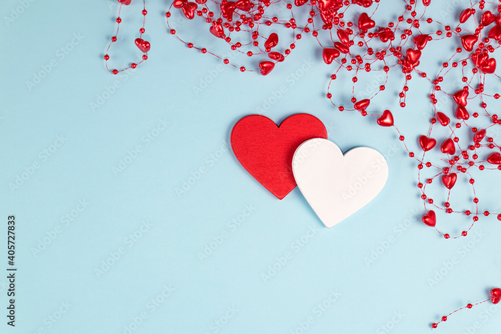 Valentine's Day background. Two hearts with red confetti, beads with hearts on pastel blue colors. Valentine's Day concept. Flat lay. Top view.