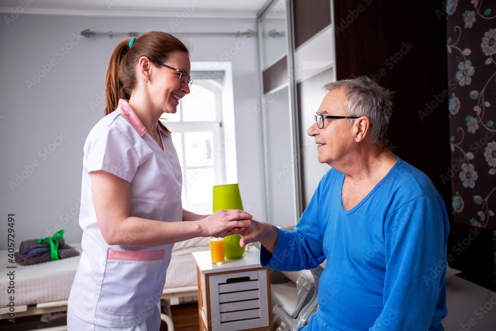 Caring nurse holding a hand of a senior man occupant in a nursing home room Caring nurse holding a hand of a senior man occupant in a nursing home room