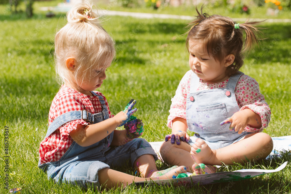 Two little girls sisters paint with finger paints Two little girls sisters paint with finger paints