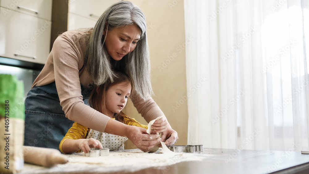 Grandmother cutting cookies from dough with little granddaughter Grandmother cutting cookies from dough with little granddaughter