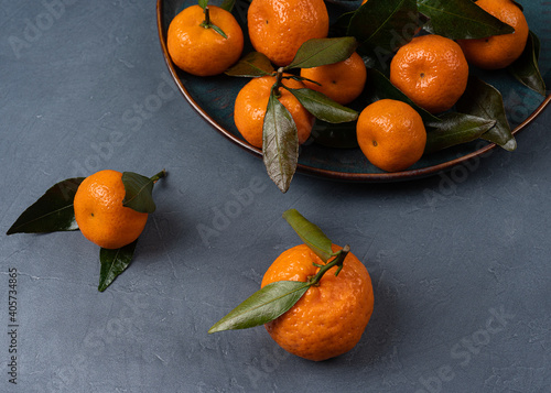 Ripe orange tangerine in a plate on a grey background