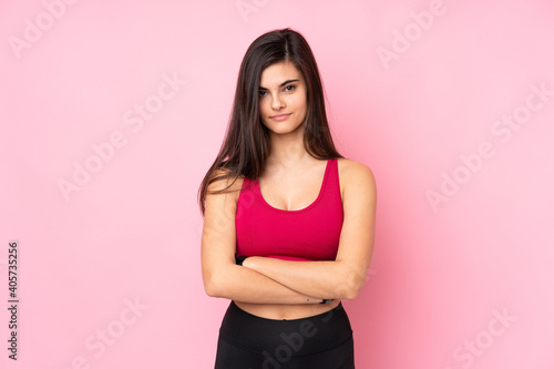 Young sport woman over isolated pink background with arms crossed