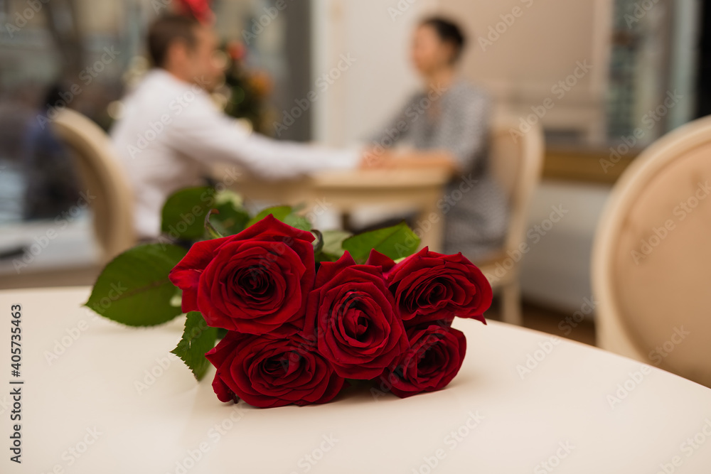 bouquet of red roses on the background of a young couple at the table bouquet of red roses on the background of a young couple at the table