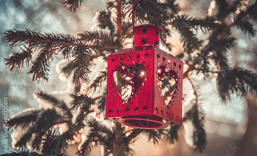 red Christmas lantern hangs on a snow-covered Christmas tree