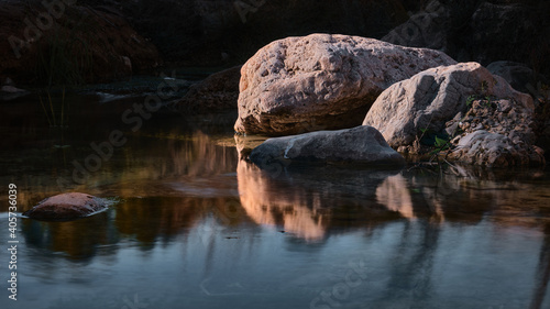 Some rocks surrounded by mirroring water in the river
