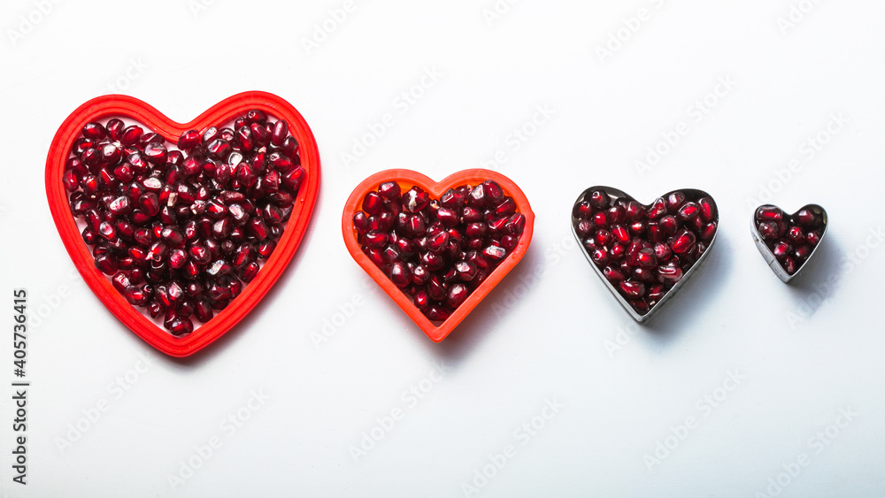 Hearts shape pomegranate seeds on white background. Valentines helthy love concept. Hearts shape pomegranate seeds on white background. Valentines helthy love concept.