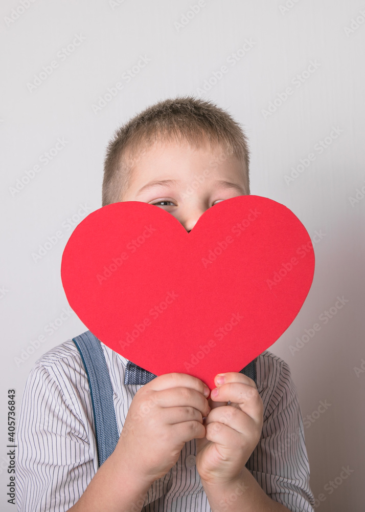 Five year old smiling boy holding a red heart symbol of love, family, hope. Backgrounds for cards on Valentine's Day or social posters about the preservation of the family and children. Five year old smiling boy holding a red heart symbol of love, family, hope. Backgrounds for cards on Valentine's Day or social posters about the preservation of the family and children.