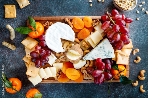 Big cheese board with appetizer assortment. Grape, cheese, nuts, jam and bread.