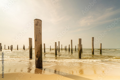Long exposure seascape in retro colors. Taken at the North Sea in Petten with the pole village in the sea, Blue sky, sun and shodows. Focus on foreground