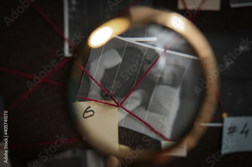 Fototapeta kuchenna Looking at detective board through magnifying glass, closeup
