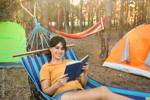 Woman with book resting in comfortable hammock outdoors