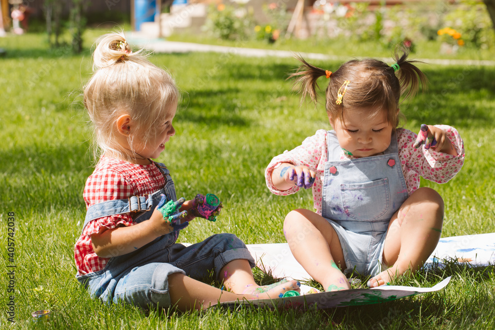 Two little girls sisters paint with finger paints Two little girls sisters paint with finger paints
