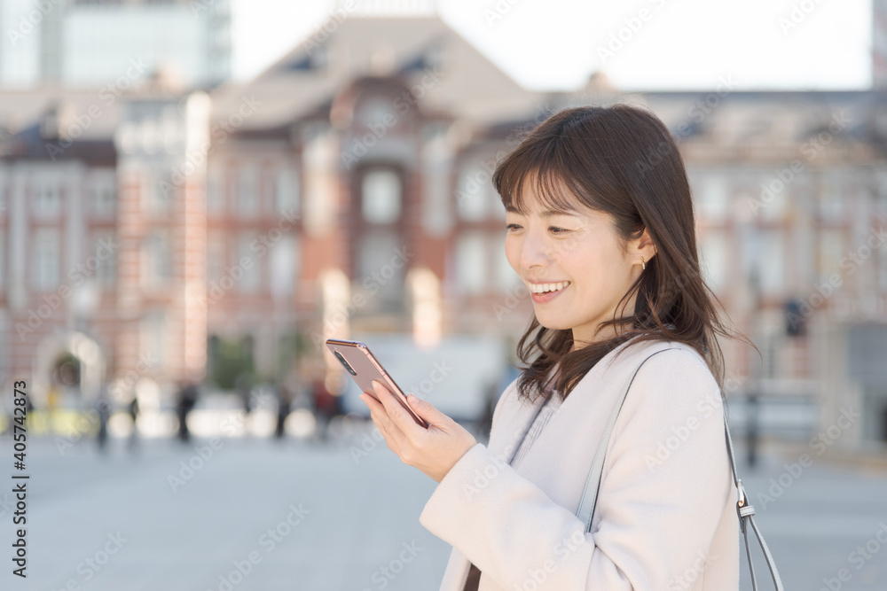 東京駅でスマートフォンで通話する女性