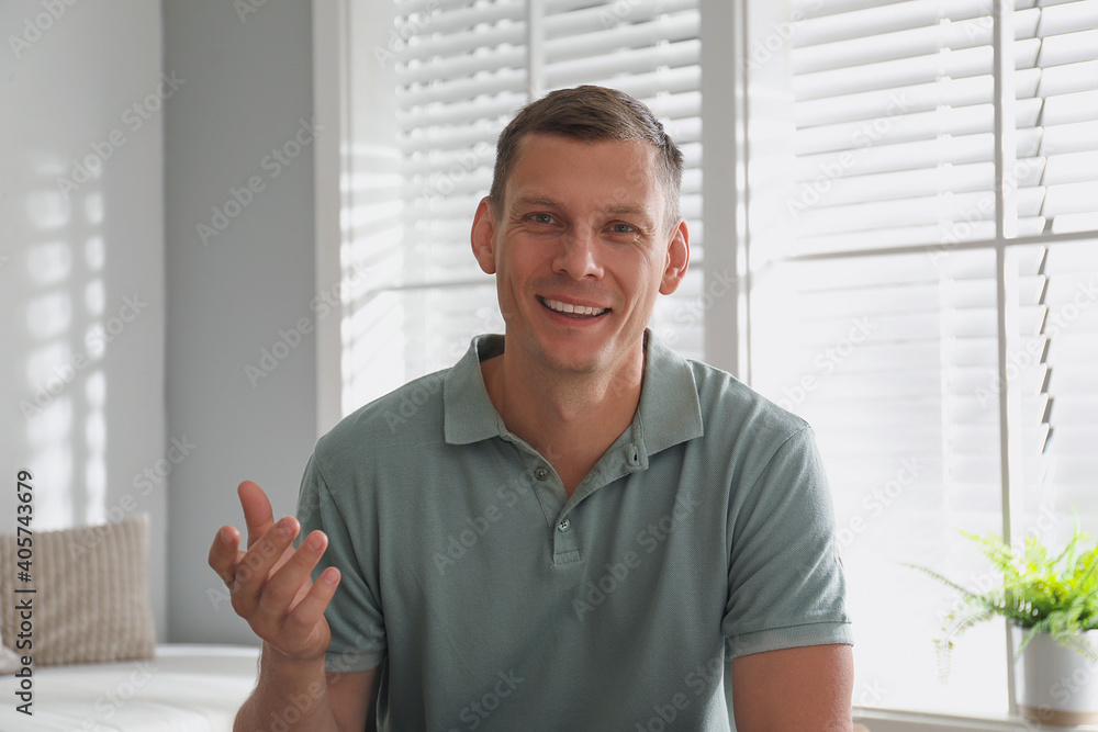 Man talking to his coworkers through video conference indoors, view from webcam Man talking to his coworkers through video conference indoors, view from webcam