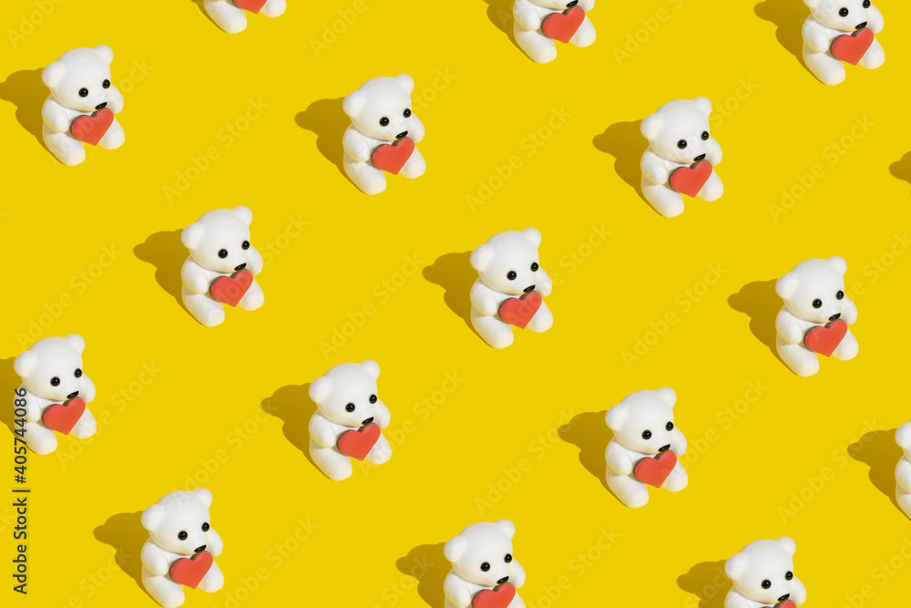 Pattern made with white teddy bears holding a heart shaped cookie on modern trendy yellow background. Minimal Valentines, romantic or love concept. Copy space.