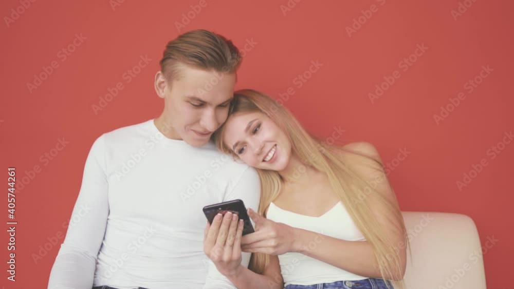 Young woman and man look at the phone together and smile Young woman and man look at the phone together and smile