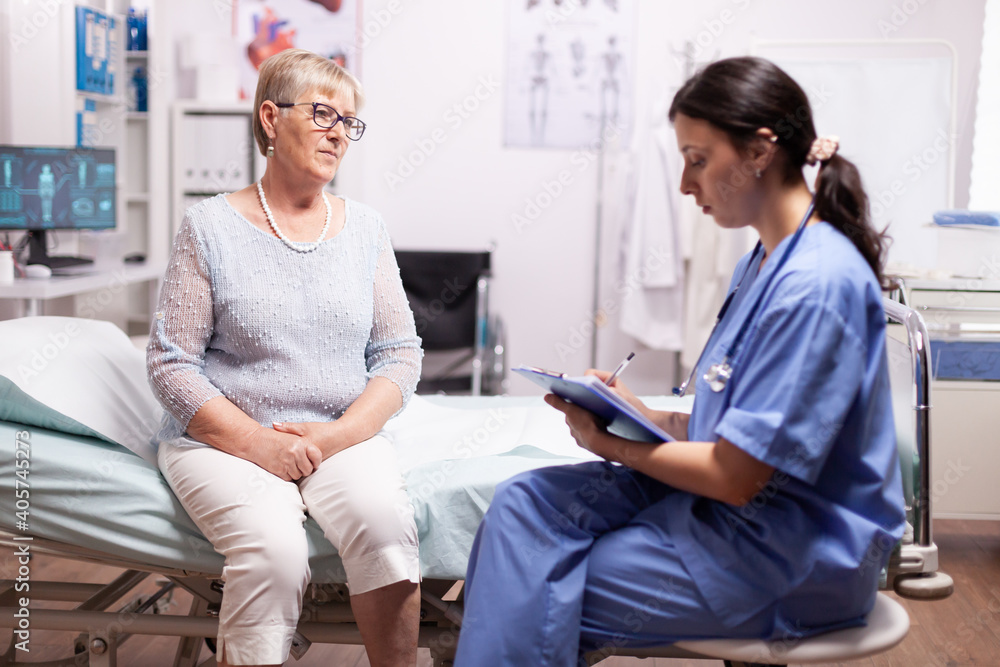 Nurse writing prescription on clipboard discussing with senior man. Elderly patient having a converstation with medical stuff in private clinic during consultation. Nurse writing prescription on clipboard discussing with senior man. Elderly patient having a converstation with medical stuff in private clinic during consultation.