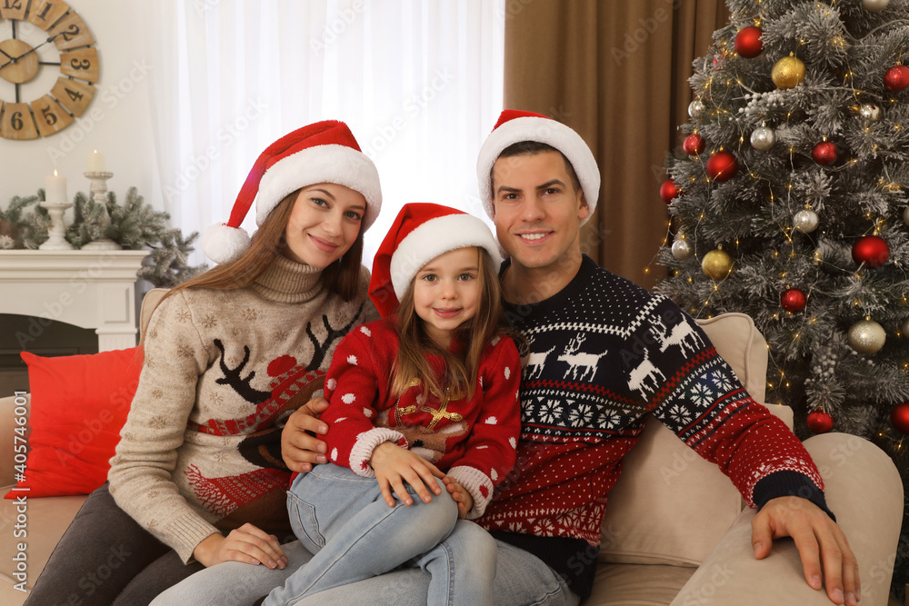 Happy family in Santa hats near Christmas tree at home Happy family in Santa hats near Christmas tree at home