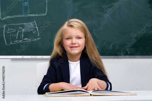 Happy schoolgirl sitting at desk