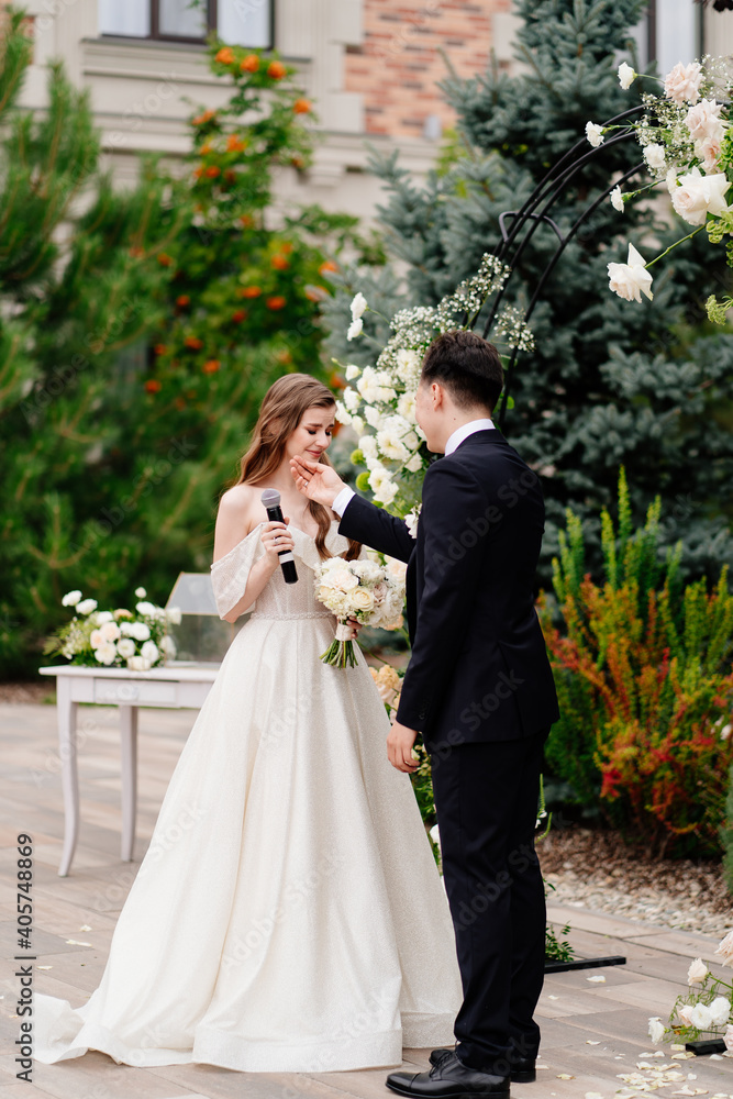 wedding ceremony in arch of living flowers. bride says wedding vow and cry wedding ceremony in arch of living flowers. bride says wedding vow and cry