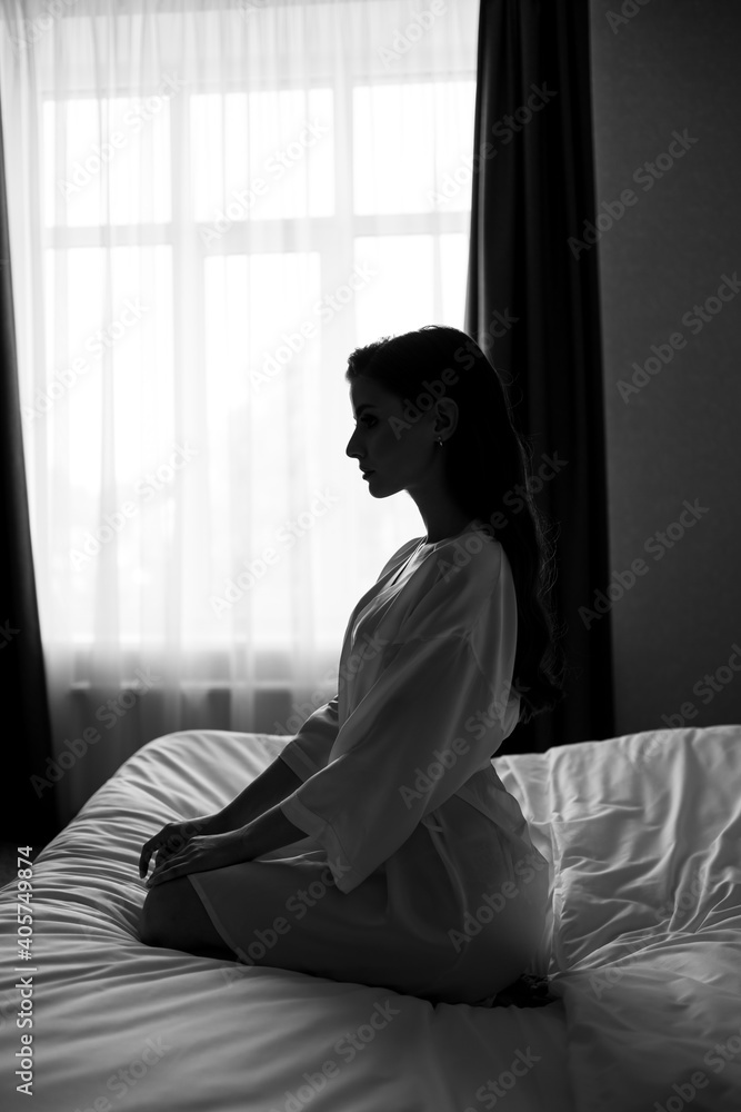 silhouette. beautiful woman with makeup, long hair sits in white robe on bed silhouette. beautiful woman with makeup, long hair sits in white robe on bed