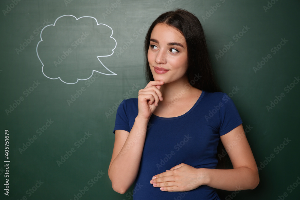 Pregnant woman thinking about baby name near green chalkboard