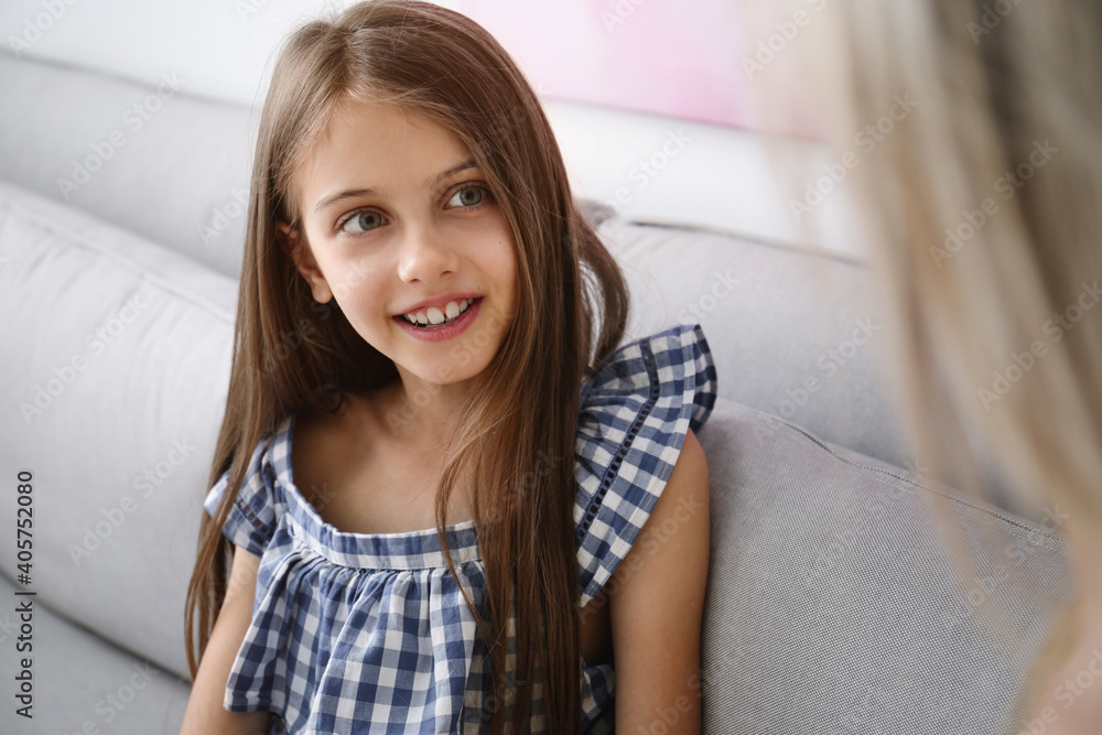 Cute girl with her mother sitting in sofa at home Cute girl with her mother sitting in sofa at home