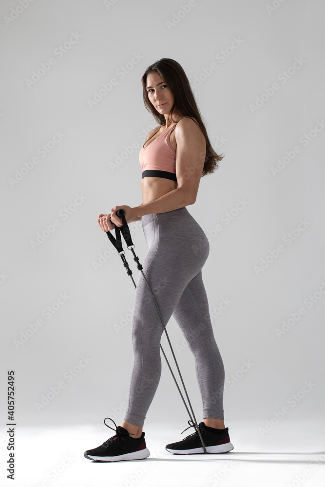 young woman doing fitness with an expander on white background , Woman in sportswear doing exercises with expander young woman doing fitness with an expander on white background , Woman in sportswear doing exercises with expander