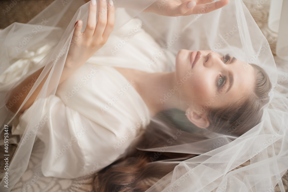 a beautiful young woman in robe is lying under a veil. a beautiful young woman in robe is lying under a veil.