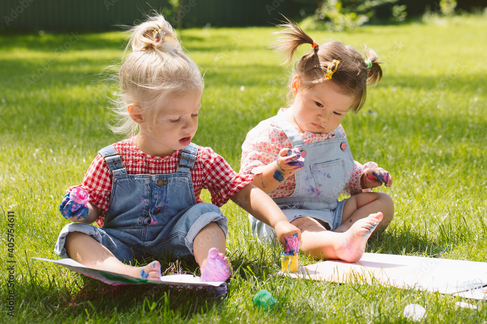 Two little girls sisters paint with finger paints Two little girls sisters paint with finger paints